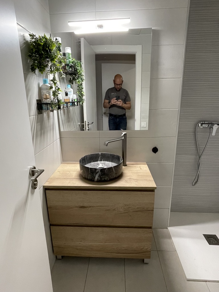 Baño renovado con mueble de madera y lavabo de piedra